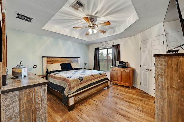 228 Old Firetower Rd, Bastrop, TX 78602 - bedroom featuring a raised ceiling, light wood-style floors, and a ceiling fan