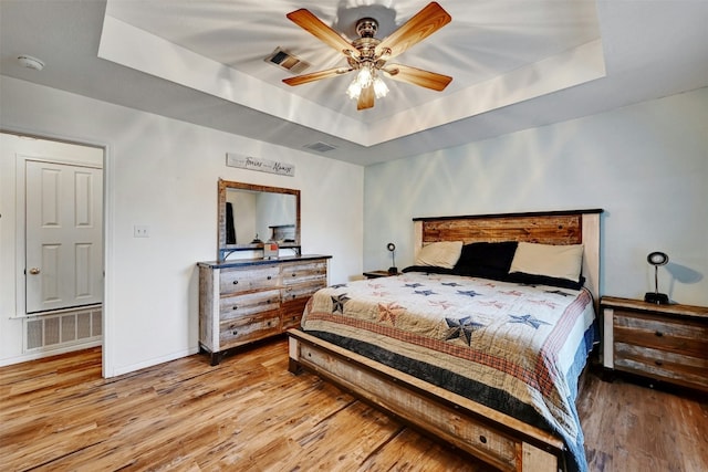 bedroom featuring a tray ceiling, ceiling fan, and hardwood / wood-style flooring