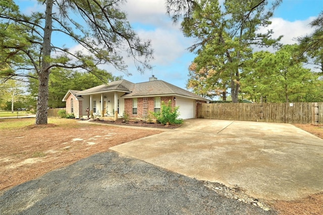 228 Old Firetower Rd, Bastrop, TX 78602 - view of property exterior with asphalt driveway, an attached garage, brick siding, a porch, and a chimney