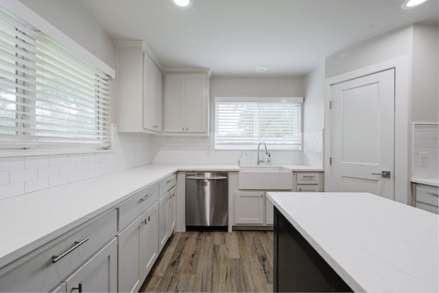 kitchen featuring dishwasher, sink, dark hardwood / wood-style flooring, backsplash, and white cabinets