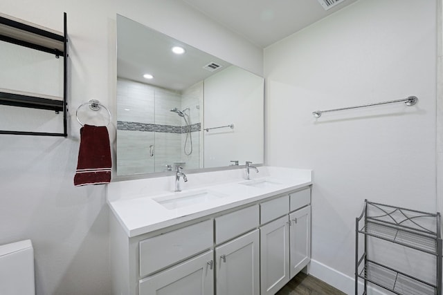 bathroom featuring hardwood / wood-style floors, vanity, a shower with shower door, and toilet