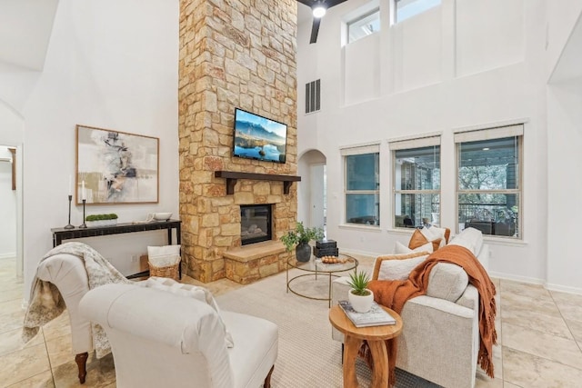 living room featuring a stone fireplace, high vaulted ceiling, and light tile patterned flooring