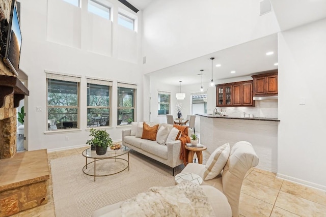 living room with a fireplace, plenty of natural light, and a towering ceiling