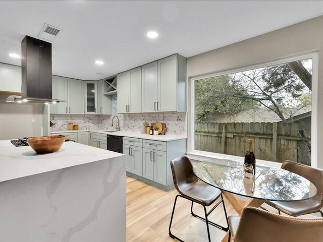 kitchen featuring sink, wall chimney exhaust hood, black dishwasher, tasteful backsplash, and light hardwood / wood-style floors