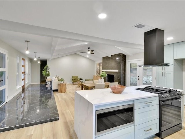 kitchen with black range with gas cooktop, island range hood, lofted ceiling with beams, white cabinets, and stainless steel microwave