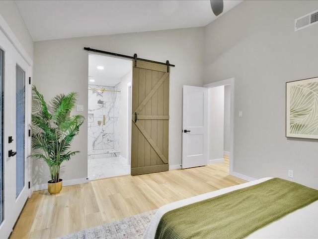 bedroom with connected bathroom, ceiling fan, a barn door, vaulted ceiling, and hardwood / wood-style flooring