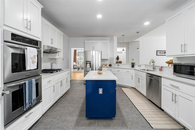 kitchen featuring sink, a center island, kitchen peninsula, pendant lighting, and appliances with stainless steel finishes