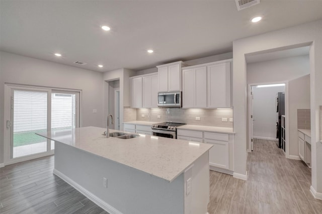 kitchen featuring stainless steel appliances, an island with sink, sink, and white cabinets