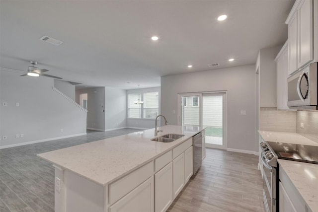 kitchen featuring stainless steel appliances, an island with sink, sink, and white cabinetry