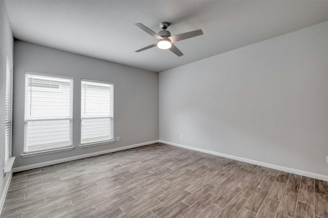 spare room featuring ceiling fan, light hardwood / wood-style floors, and a healthy amount of sunlight