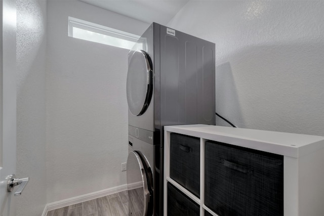 laundry area with stacked washing maching and dryer and light hardwood / wood-style flooring