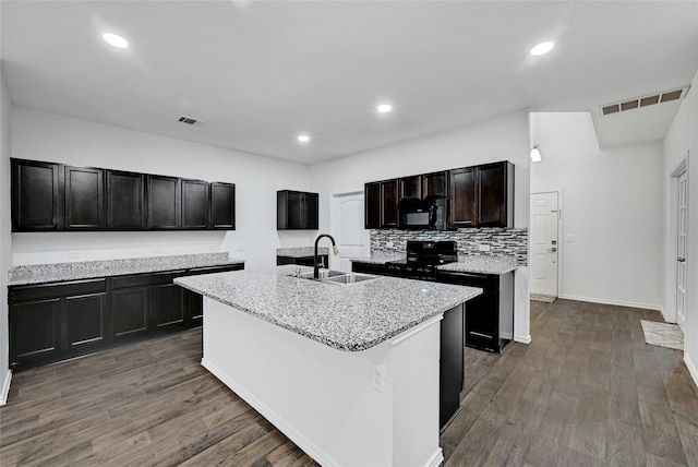 kitchen featuring a center island with sink, black appliances, dark hardwood / wood-style flooring, and sink