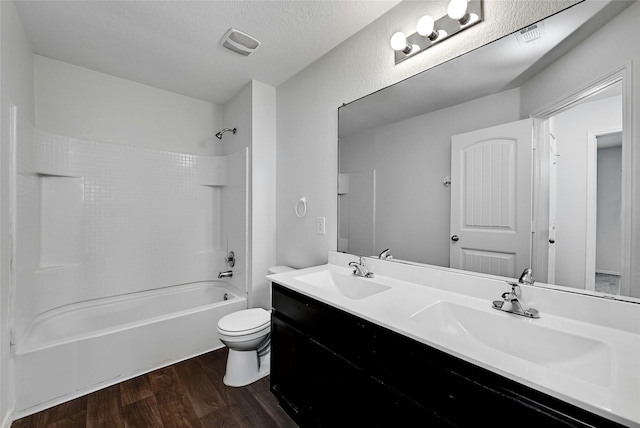 full bathroom with toilet, hardwood / wood-style flooring, a textured ceiling, shower / tub combination, and vanity