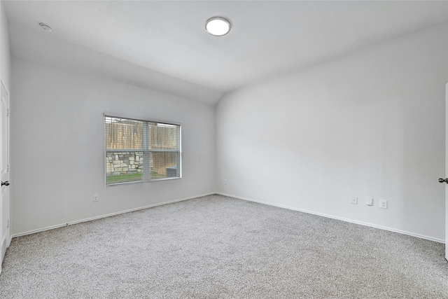 carpeted empty room with vaulted ceiling