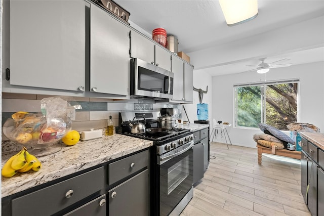 kitchen featuring ceiling fan, stainless steel appliances, light stone counters, backsplash, and light hardwood / wood-style floors