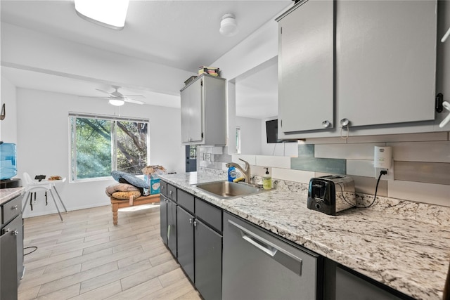 kitchen with decorative backsplash, light wood-type flooring, stainless steel dishwasher, gray cabinetry, and sink