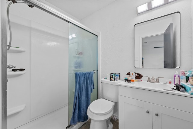 bathroom featuring vanity, a shower with shower door, and toilet