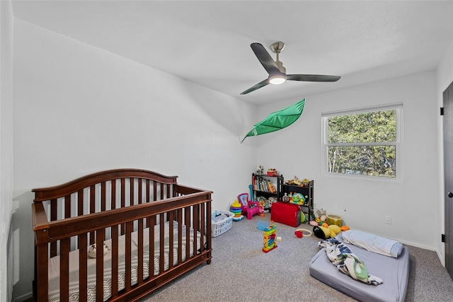 bedroom featuring ceiling fan, a crib, and carpet floors