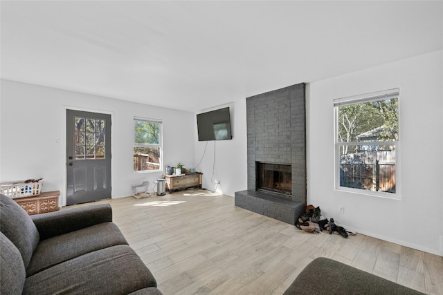 living room featuring light wood-type flooring and a brick fireplace