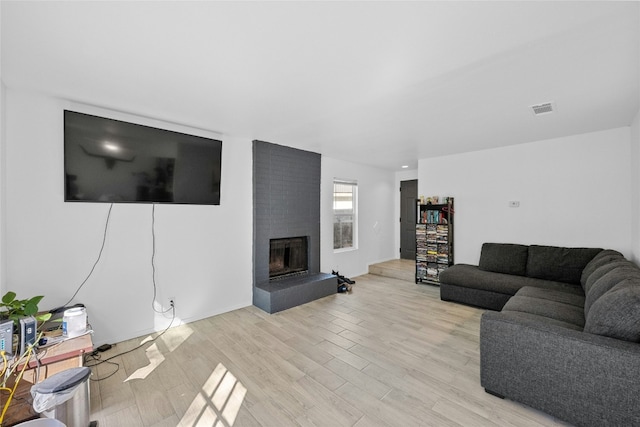 living room with a brick fireplace and light hardwood / wood-style flooring