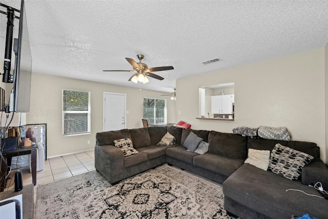 tiled living room with ceiling fan and a textured ceiling