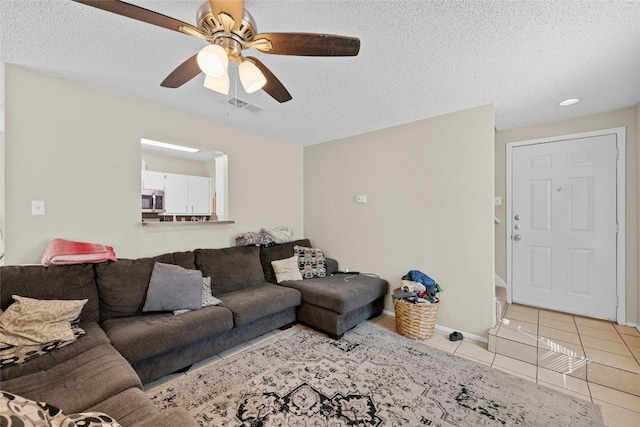 tiled living room with ceiling fan and a textured ceiling