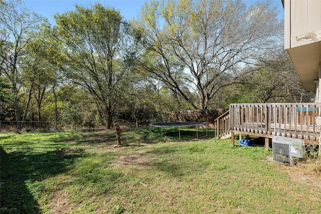 view of yard with a trampoline and a wooden deck