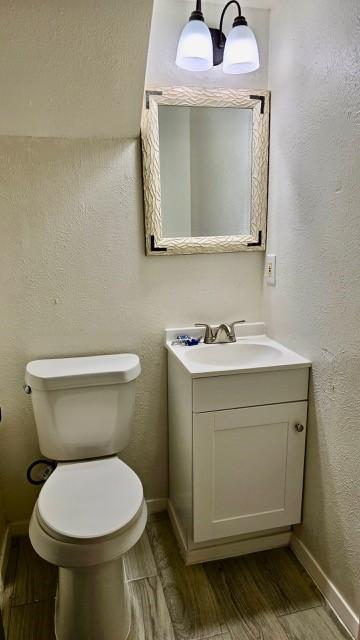 bathroom featuring wood-type flooring, vanity, and toilet