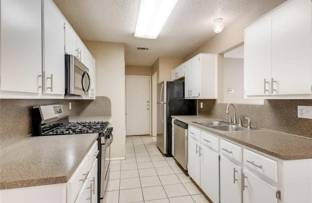 kitchen featuring appliances with stainless steel finishes, a textured ceiling, sink, white cabinetry, and light tile patterned flooring