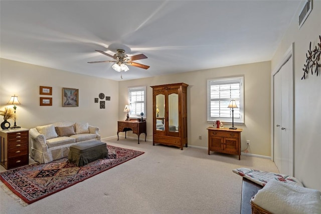 living area featuring a wealth of natural light, visible vents, light colored carpet, and ceiling fan