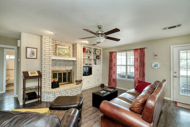 living room with dark wood-type flooring, a healthy amount of sunlight, and visible vents