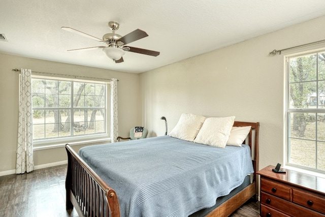 bedroom with a ceiling fan, dark wood-style floors, visible vents, and baseboards