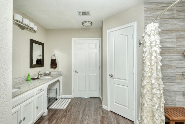 bathroom with visible vents, a sink, wood finished floors, a shower with shower curtain, and double vanity