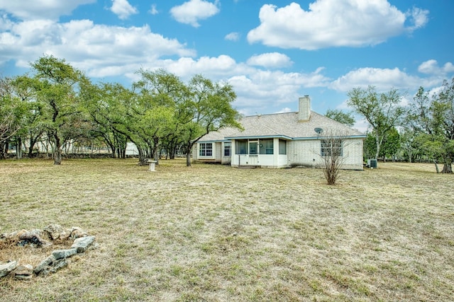 rear view of property with a yard, a chimney, and a sunroom