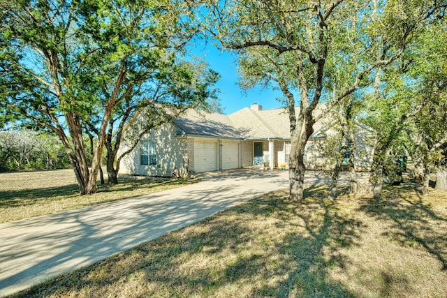 view of front of property featuring a front lawn, a chimney, concrete driveway, and an attached garage