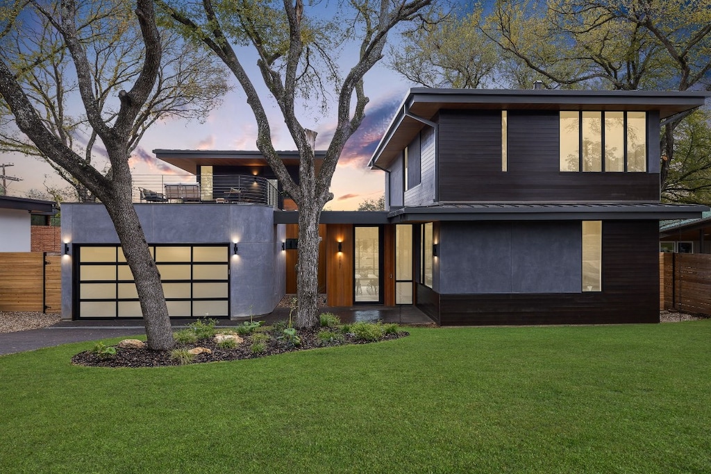 contemporary house featuring a balcony and a lawn