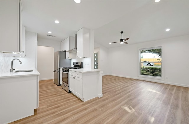 kitchen with wall chimney exhaust hood, light hardwood / wood-style floors, white cabinetry, and appliances with stainless steel finishes