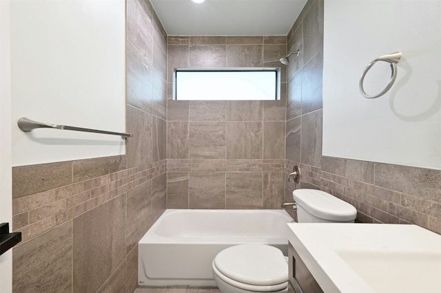 full bathroom featuring toilet, vanity, tile walls, and tiled shower / bath