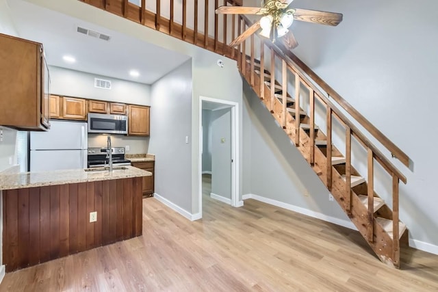 kitchen with light stone countertops, sink, light wood-type flooring, and stainless steel appliances