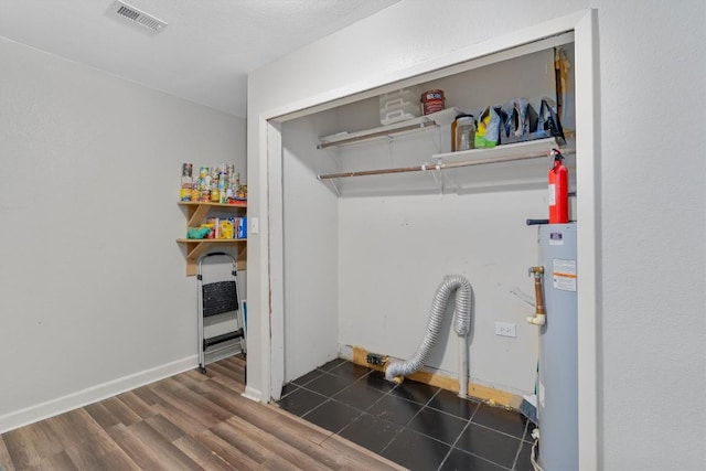 laundry area with a textured ceiling, dark hardwood / wood-style floors, and water heater