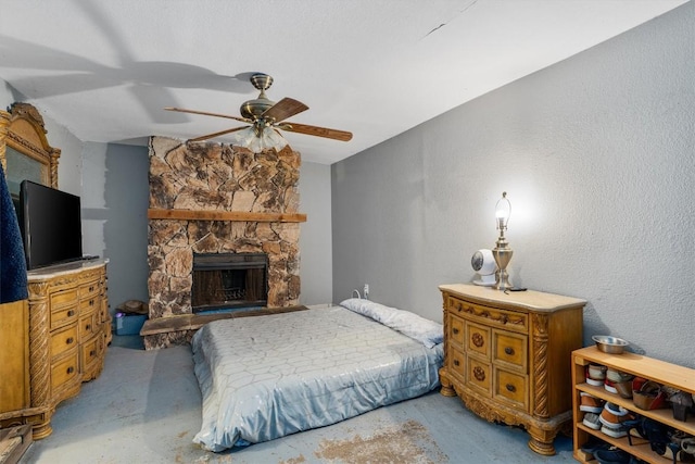 carpeted bedroom with ceiling fan and a fireplace