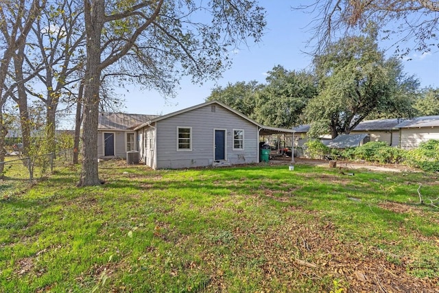 rear view of house featuring a carport, a yard, and cooling unit