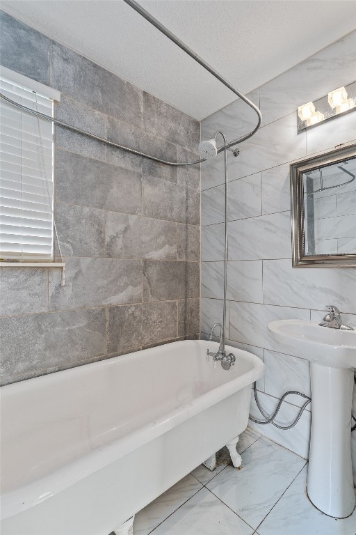 bathroom with sink, tiled shower / bath combo, and tile walls