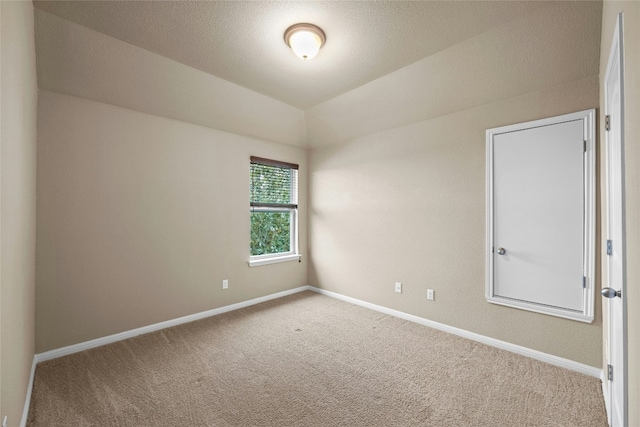 carpeted empty room featuring lofted ceiling and a textured ceiling