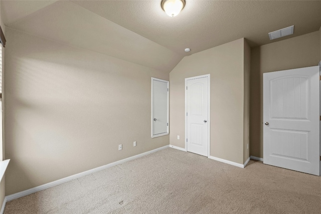 unfurnished bedroom featuring a closet, light colored carpet, and vaulted ceiling