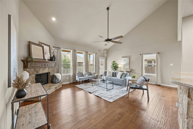 living room with ceiling fan, a fireplace, high vaulted ceiling, and dark wood-type flooring