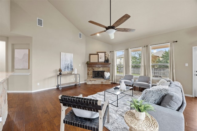 living room featuring a stone fireplace, ceiling fan, high vaulted ceiling, and dark wood-type flooring