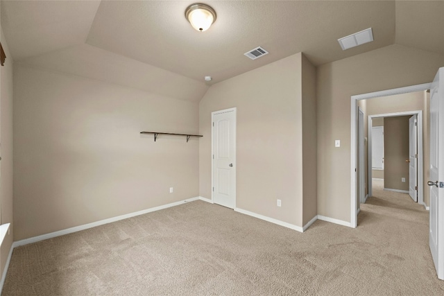 unfurnished bedroom featuring light carpet, a closet, and lofted ceiling