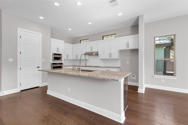 kitchen featuring a wealth of natural light, sink, dark hardwood / wood-style floors, an island with sink, and white cabinets