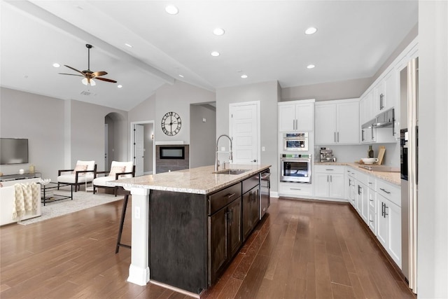 kitchen with a kitchen breakfast bar, dark wood-type flooring, sink, lofted ceiling with beams, and a center island with sink